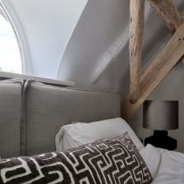 Detail bed linnen, kussen velours en houten lamp met velours kap